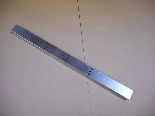 Lange, rechteckige Metallstrebe mit mehreren Löchern zur Befestigung, möglicherweise ein Kabelkanal von Remeha. Oberflächenfinish in Silber, platziert auf neutralem Untergrund.